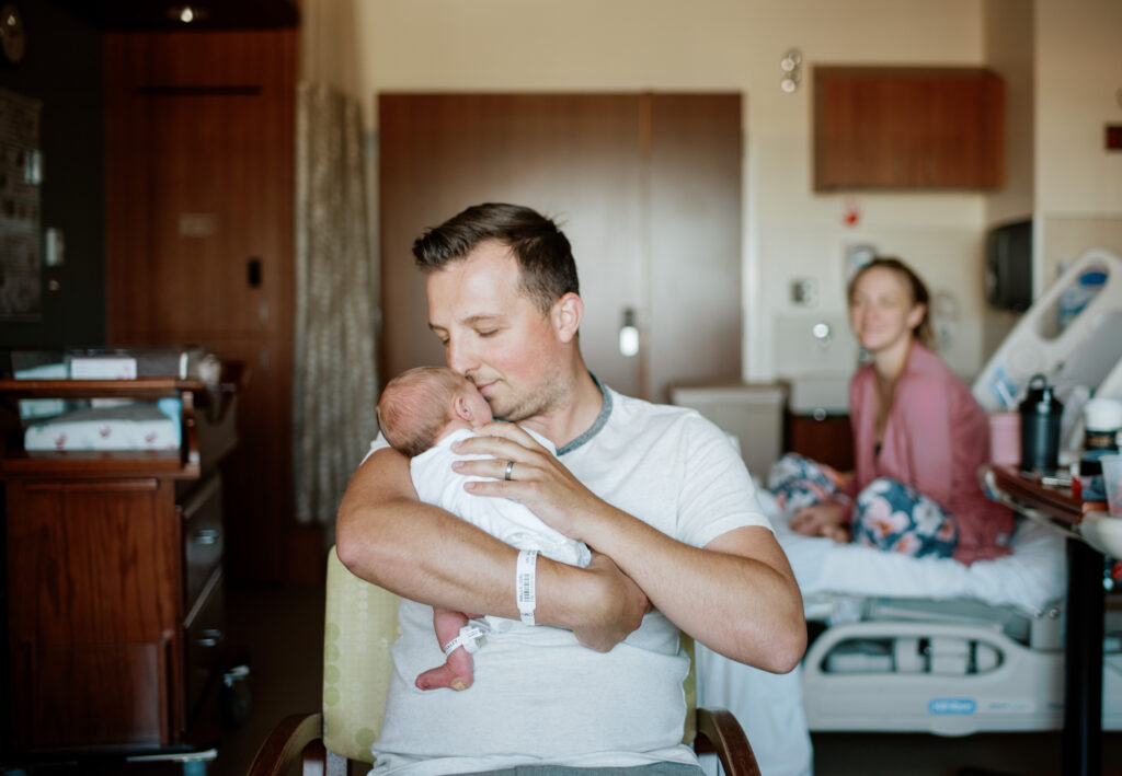 father sniffs his newborn while mother looks on