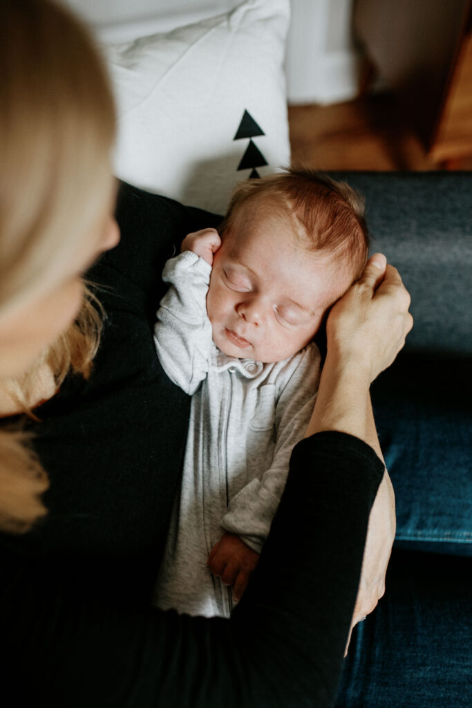 mother snuggles newborn son.