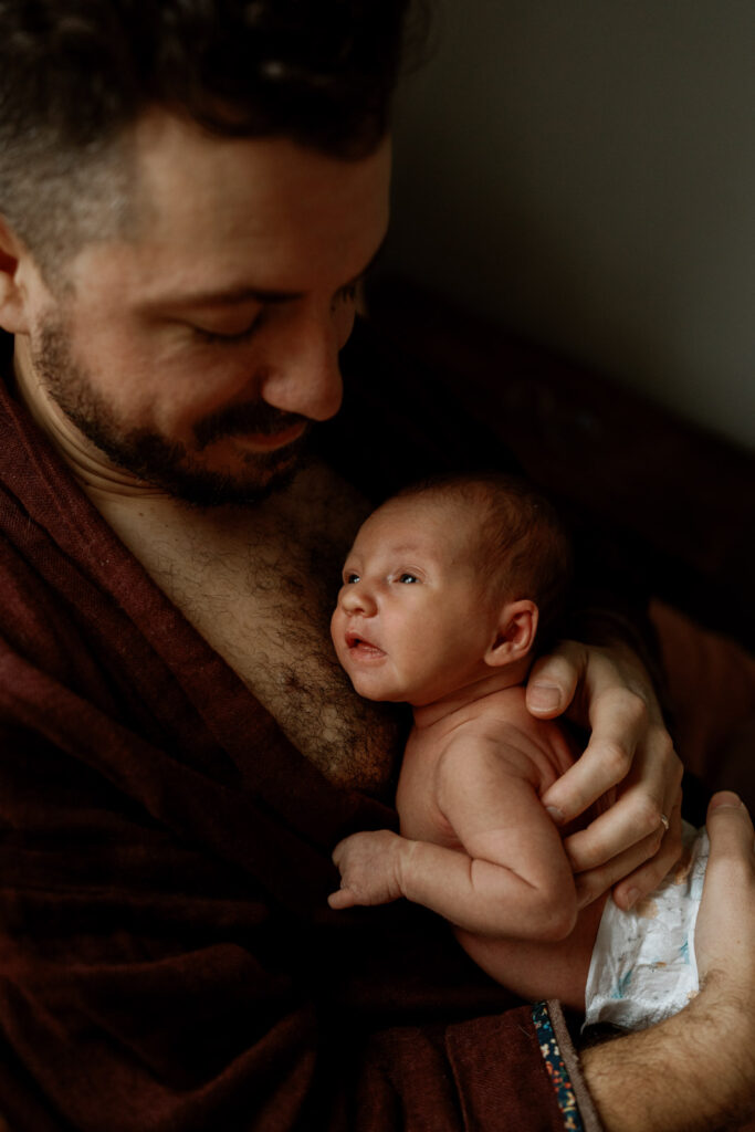 week old baby lays on her fathers chest