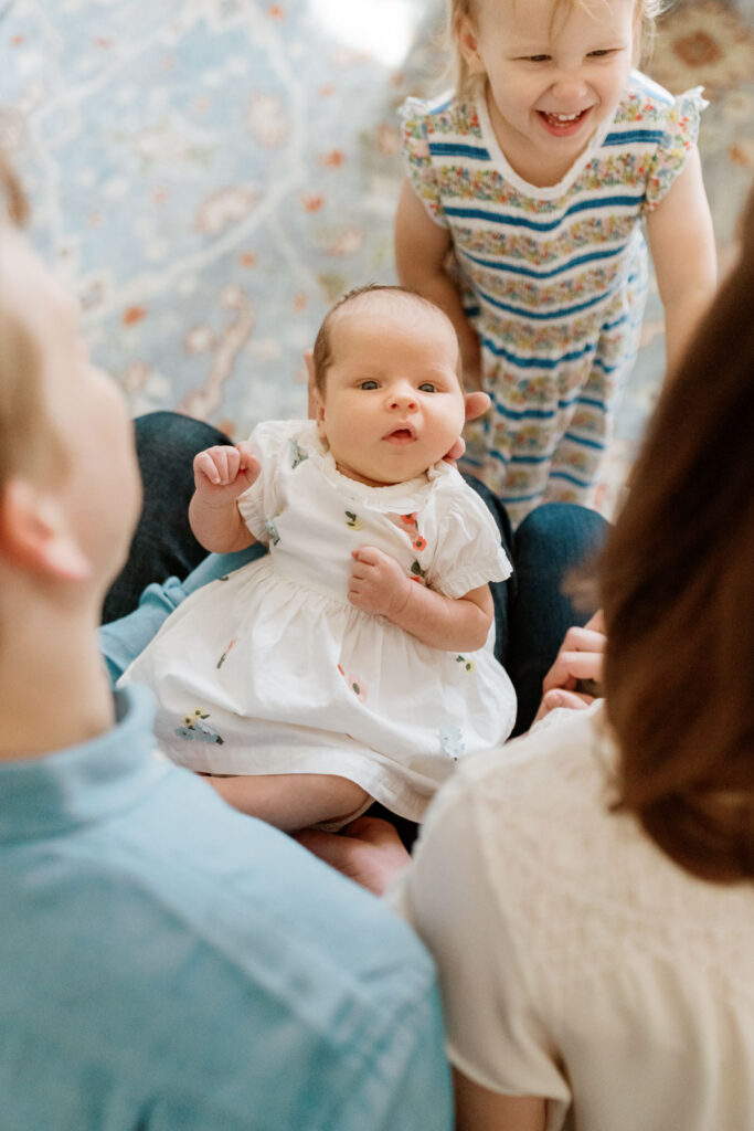 Mother, father, and daughter bond as infant girl looks directly camera.