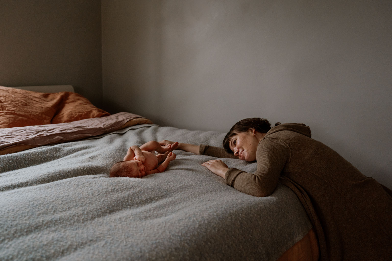 mother reclines on bed and gazes at daugher